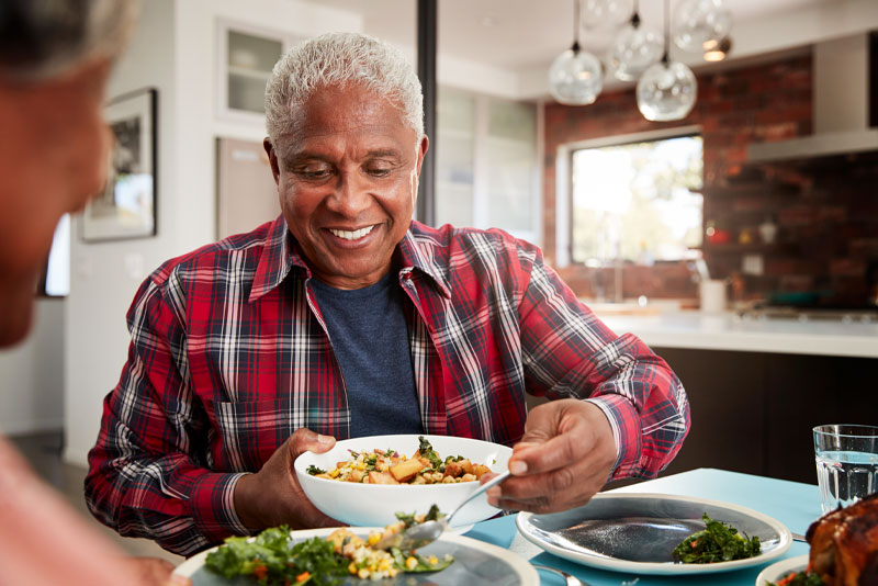 A man smiling as he eats his food because he had an anxiety-free dental implant procedure experience with sedation dentistry.