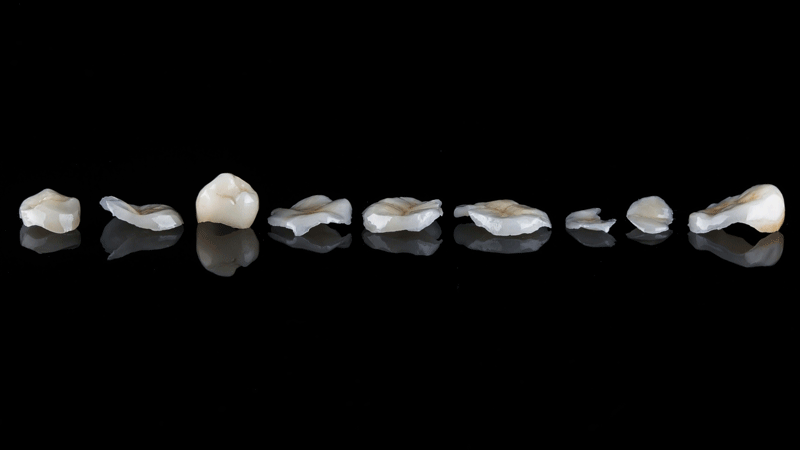 dental crowns and veneers laying on black reflective glass
