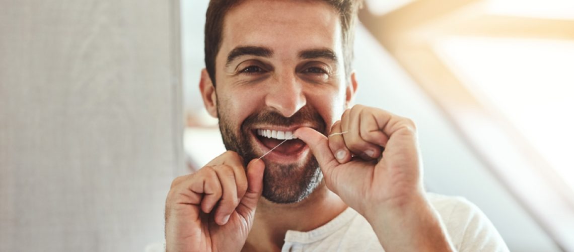 Dental floss, teeth and smile with portrait of man in bathroom for cleaning, morning and oral hygiene. Happy, cosmetics and health with face of person