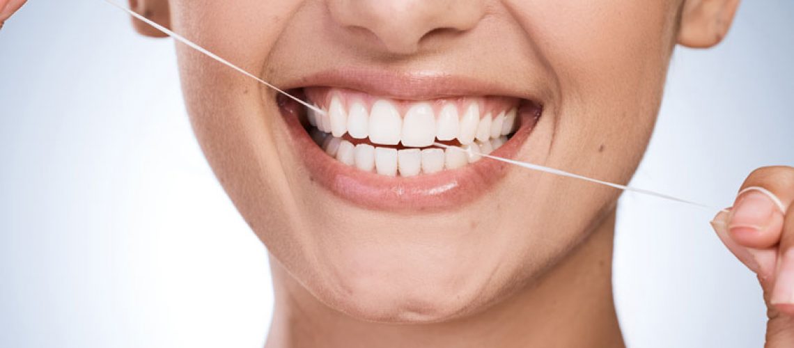 Woman, mouth and floss teeth in studio, orthodontics and cosmetics for smile on blue background