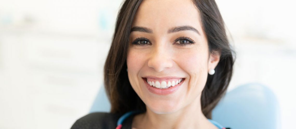 a full mouth dental implant patient smiling in a dental chair.