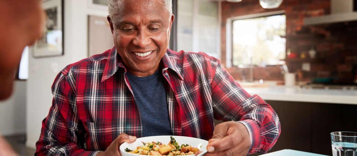 A man smiling as he eats his food because he had an anxiety-free dental implant procedure experience with sedation dentistry.