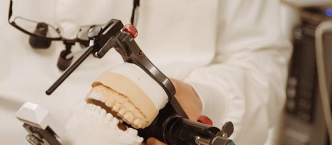 An image of a dentist holding a full mouth model.